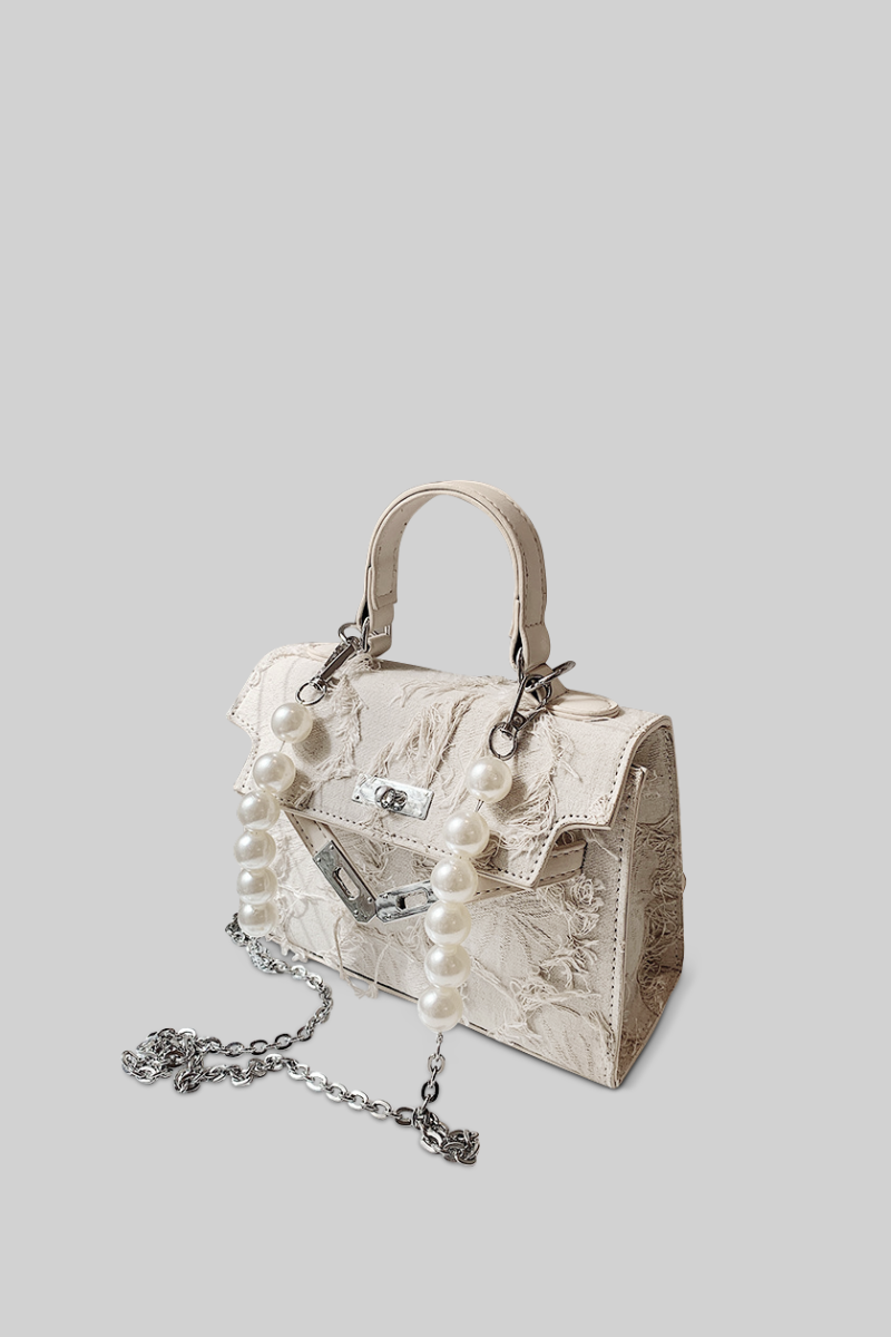 Designer handbag with pearl chain on a light gray background