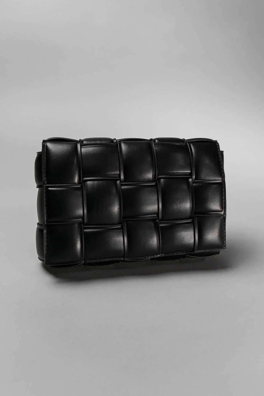 Black woven clutch bag on a gray background