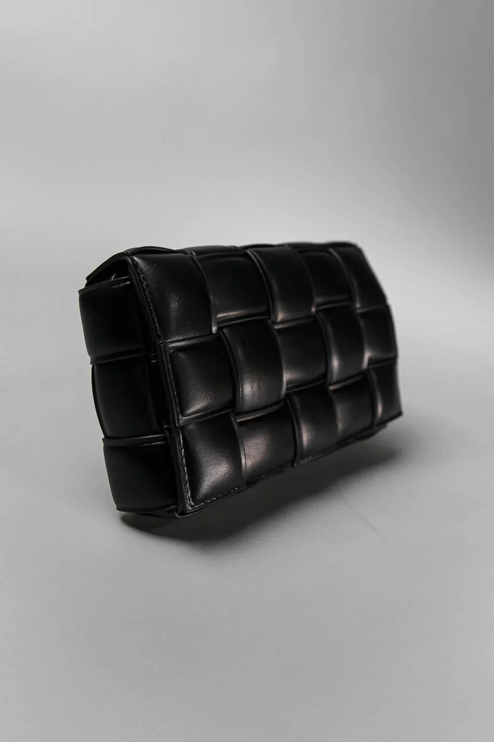 Black quilted clutch bag on a light gray background
