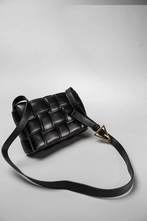 Black woven handbag with a gold clasp on a light gray background
