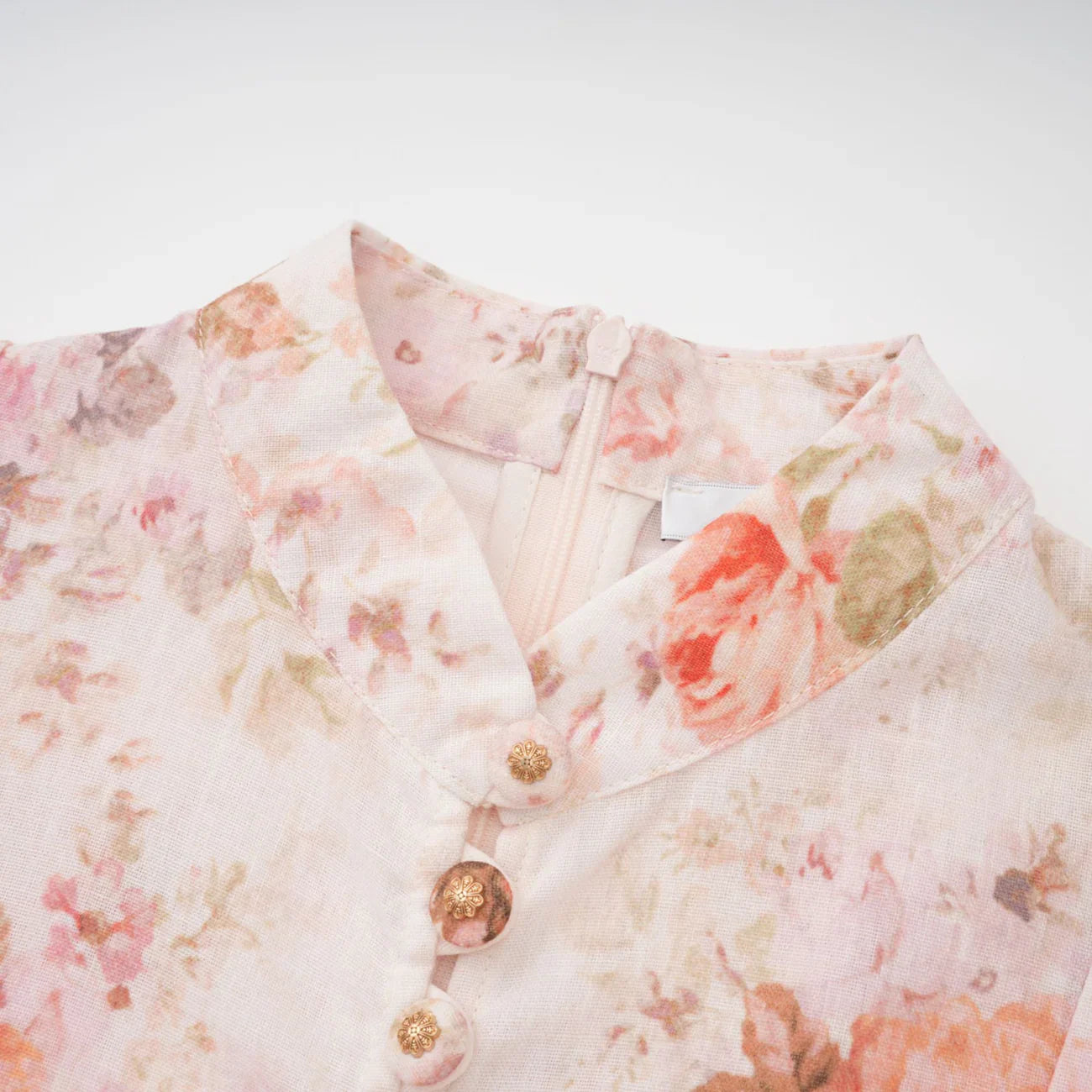 Floral patterned garment with gold buttons on a white background