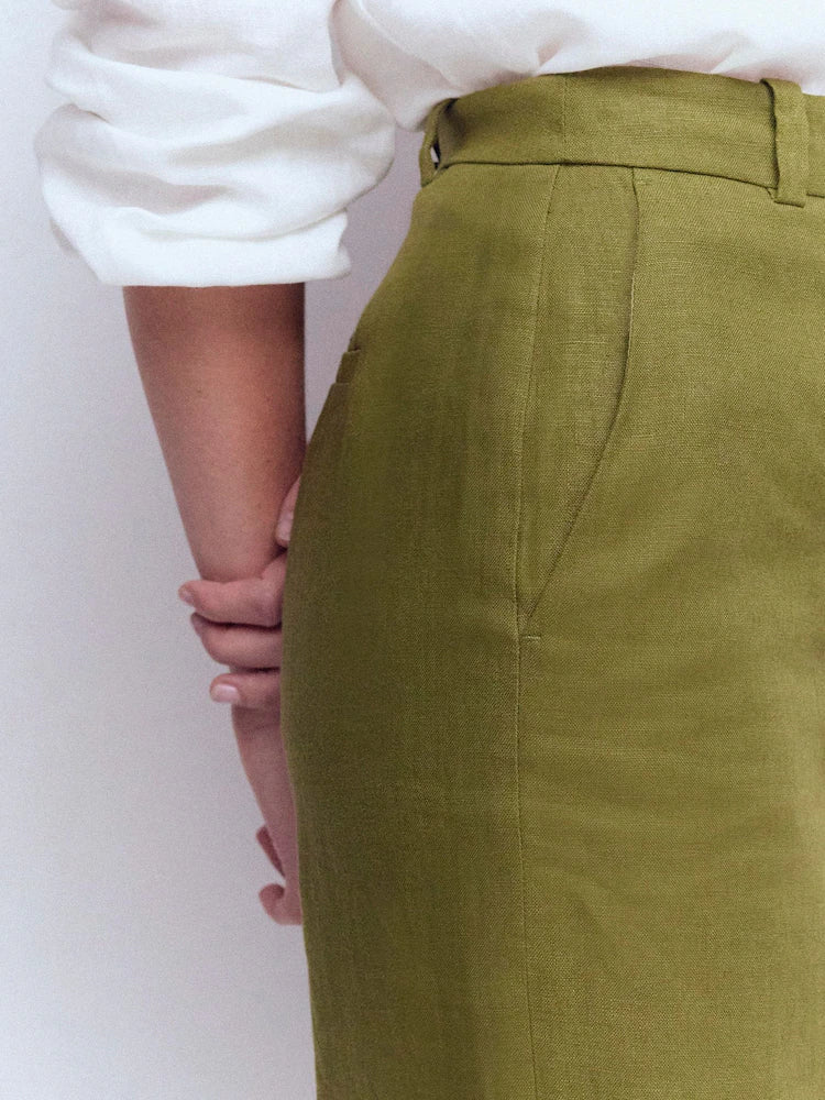 Person wearing a white shirt and green pants against a plain background