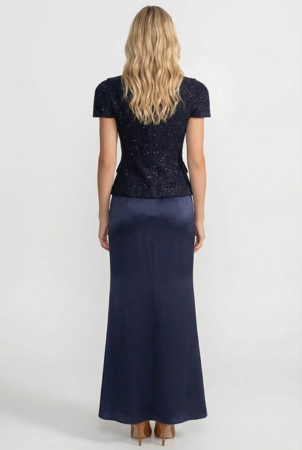 Woman wearing a navy blue dress with a sequined top on a white background