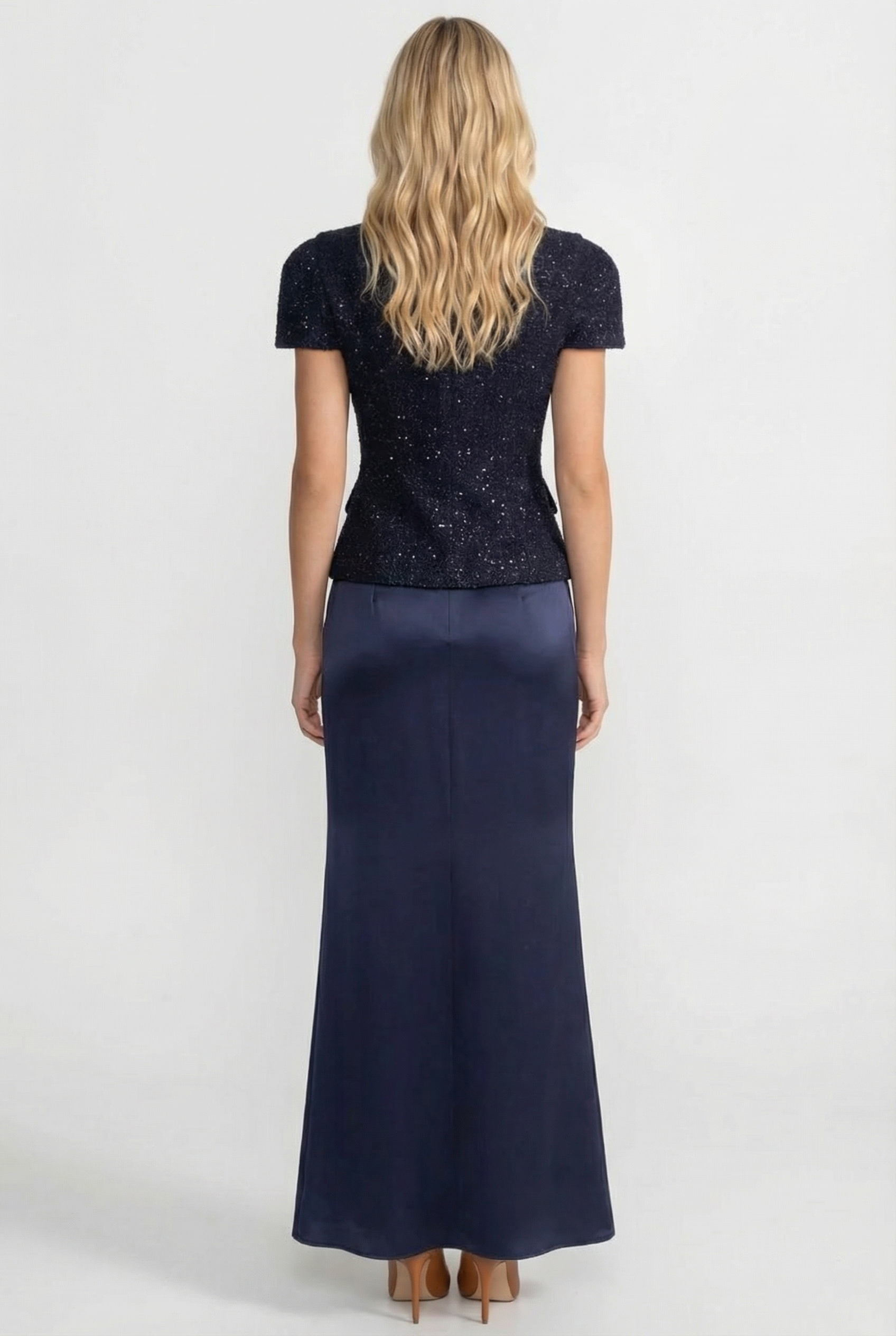 Woman wearing a navy blue dress with a sequined top on a white background