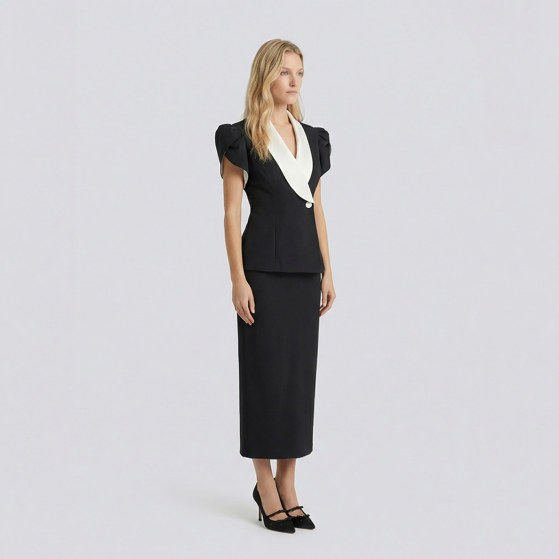 Woman wearing a black dress with a white collar against a light gray background