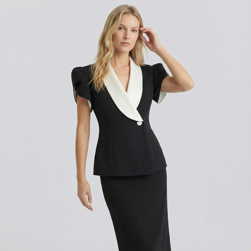 Woman wearing a black dress with a white collar against a light gray background