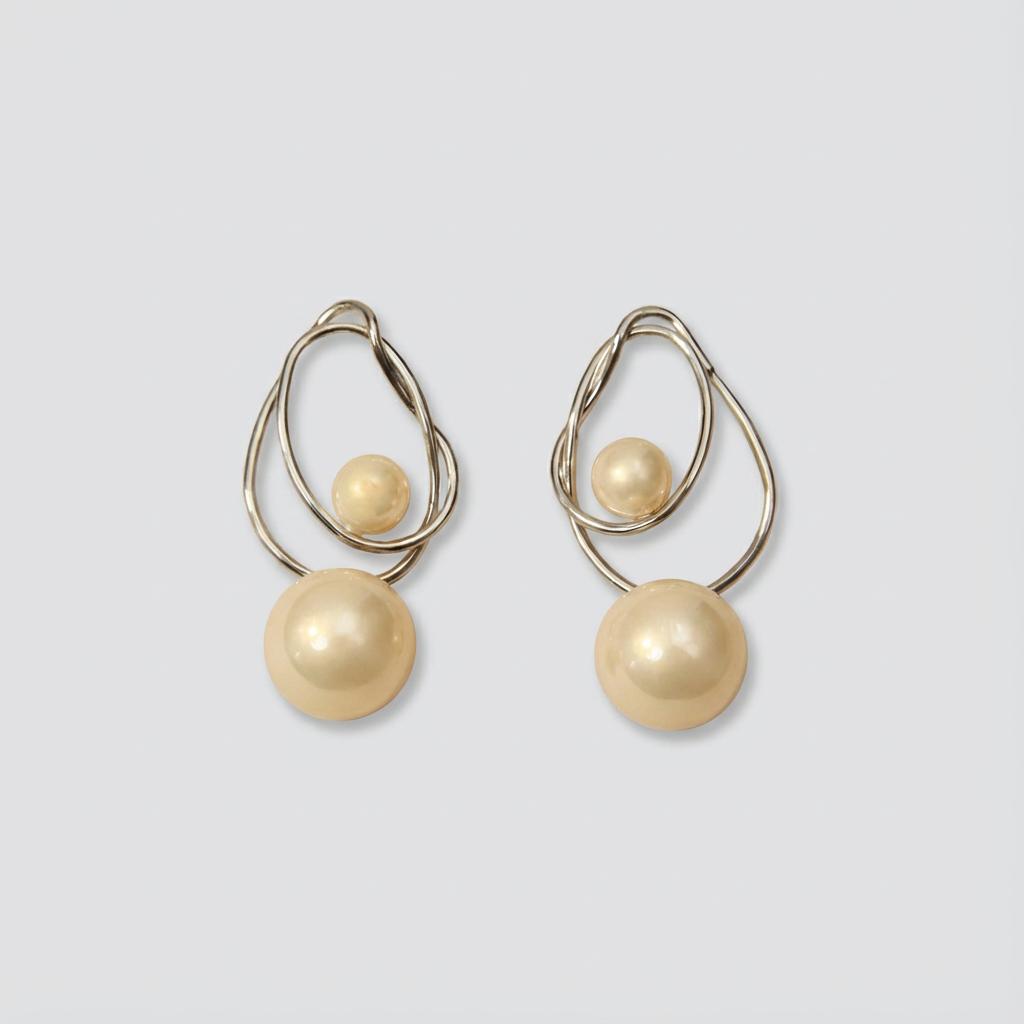 Pair of gold earrings with spherical beads on a light gray background