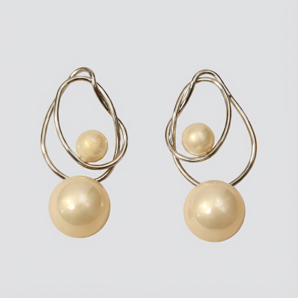Pair of gold earrings with spherical beads on a light gray background