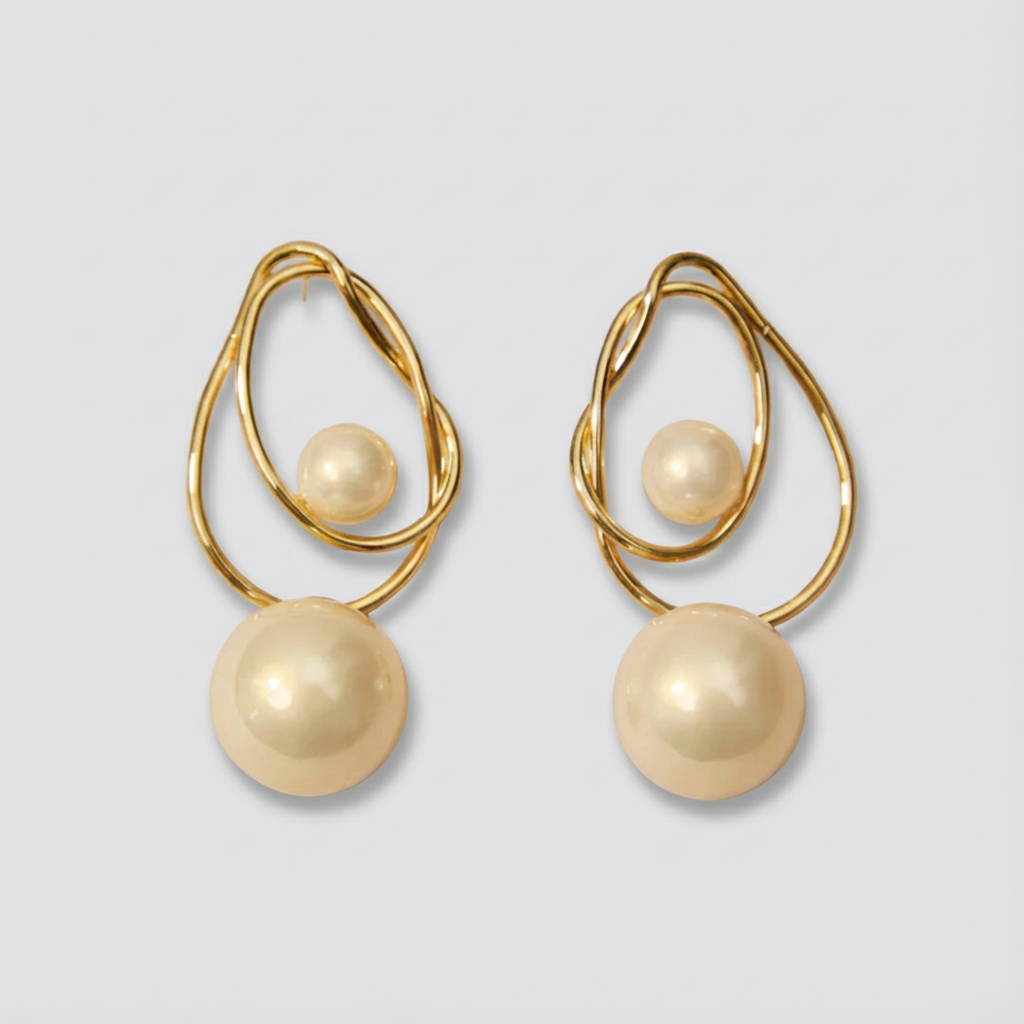Gold earrings with pearl-like beads on a light gray background