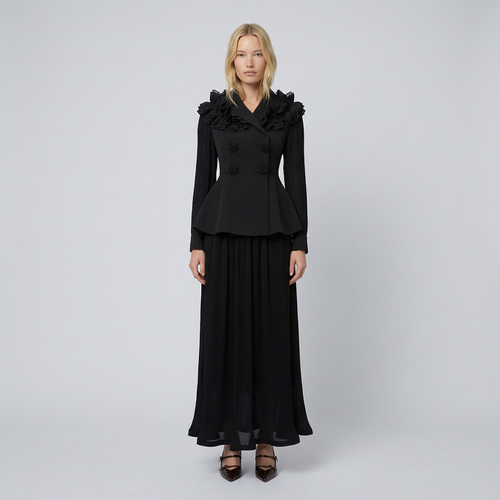 Woman wearing a black outfit with ruffled details on a gray background