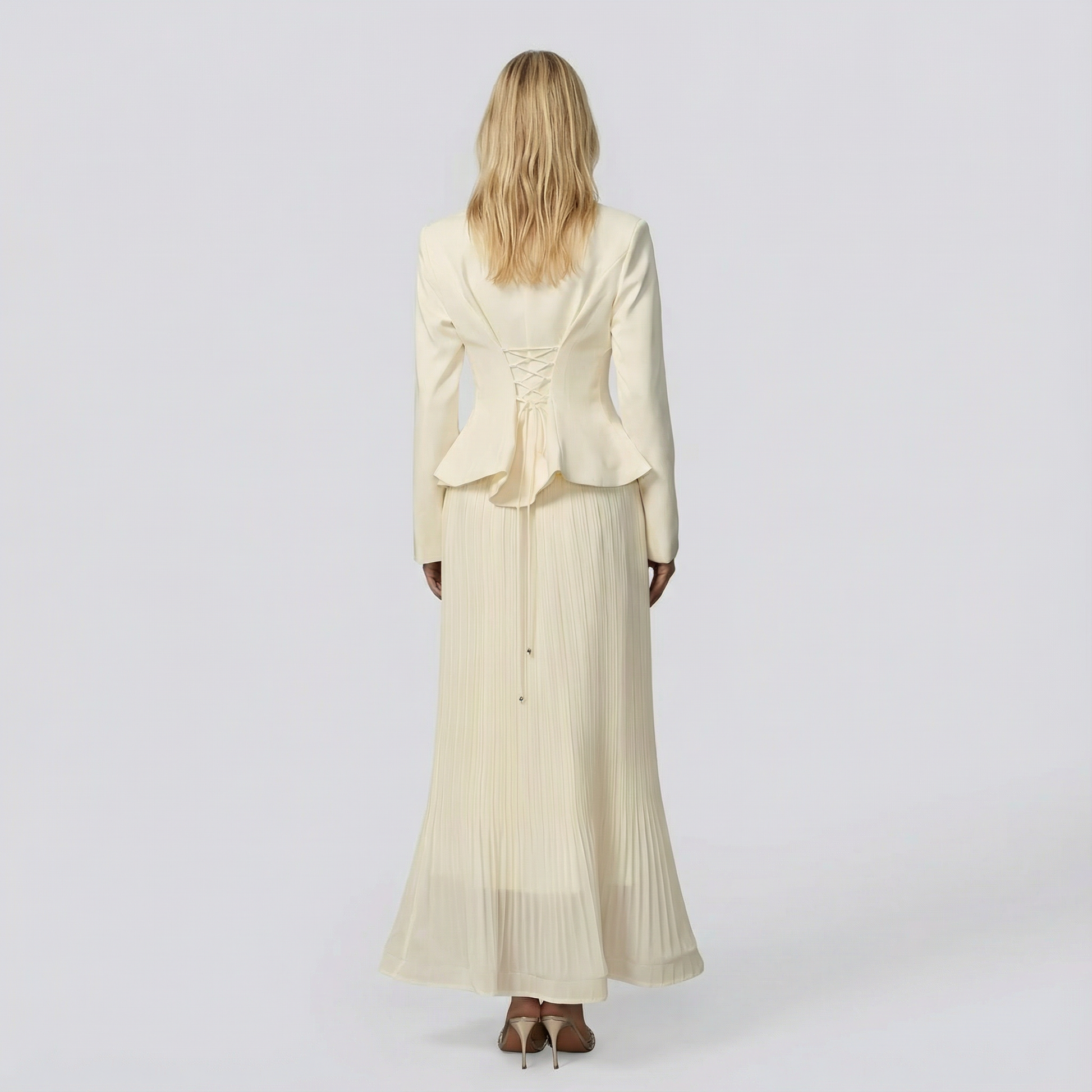 Woman wearing a beige outfit with a long skirt on a white background