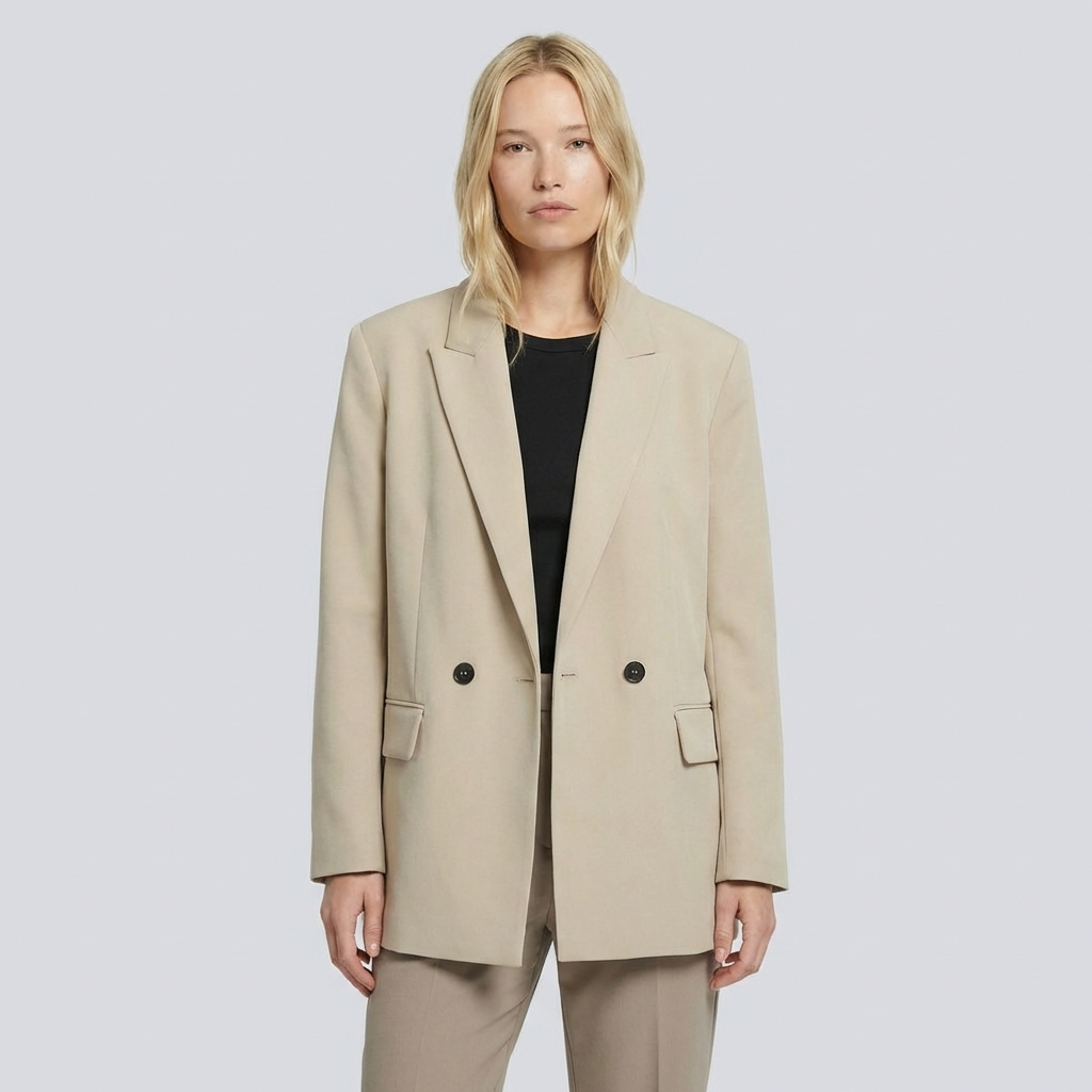 Woman wearing a beige blazer over a black top on a light gray background